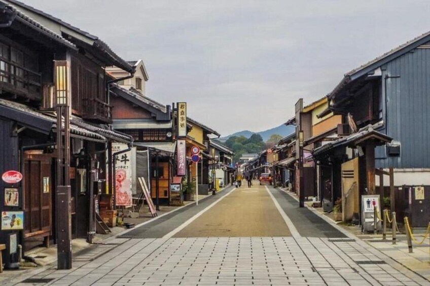 A traditional street lined with wooden buildings, a clear sky, and distant mountains. 1