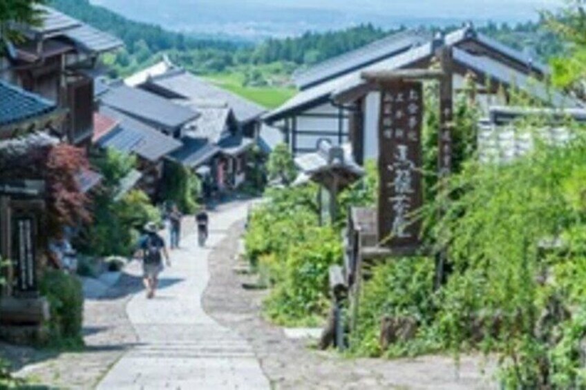 A traditional Japanese village with wooden houses, a stone pathway, and a sign with Japanese characters. 3