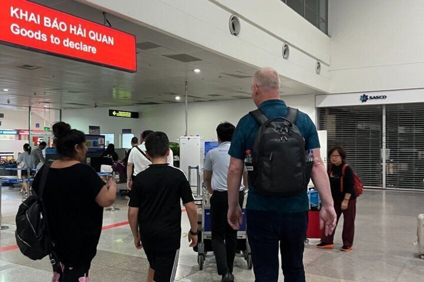 A busy airport terminal with people walking towards the 'Goods to declare' sign. 4