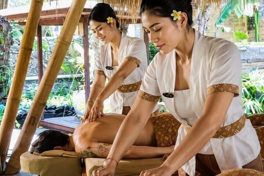 A massage session in a tropical setting with bamboo structures and lush greenery. 4