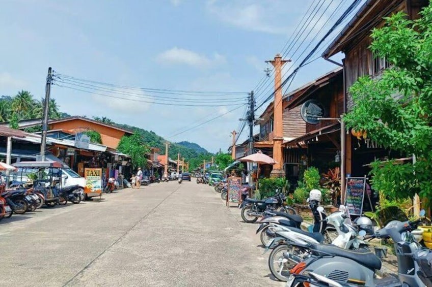 A street lined with parked motorcycles, buildings, and a sign for a taxi service. 3