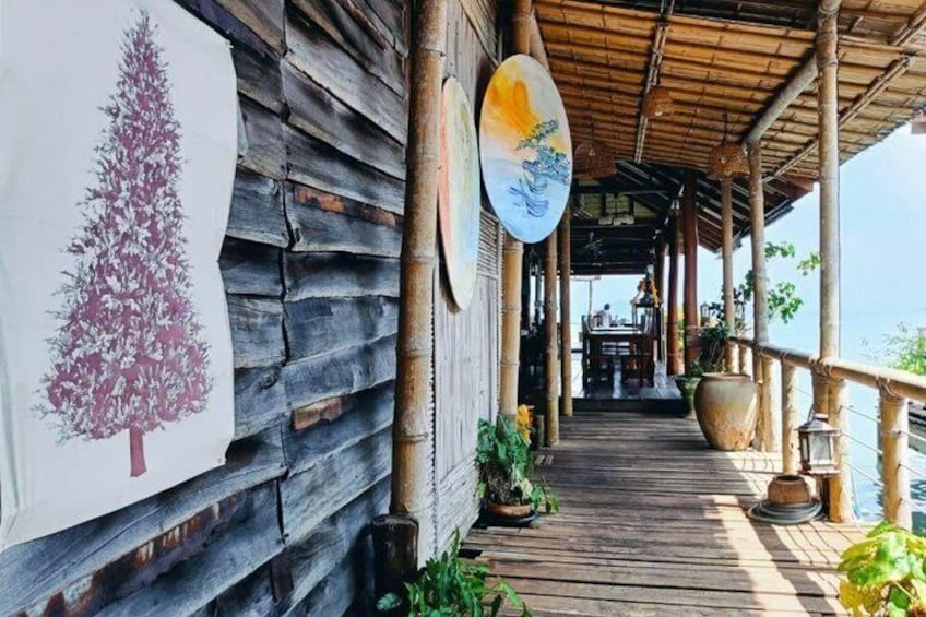 A wooden deck with a mural, a lantern, and a view of the ocean. 4