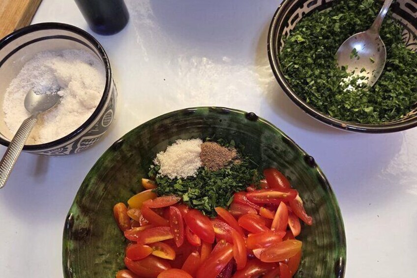 A bowl of chopped tomatoes, parsley, and spices on a kitchen counter. 5