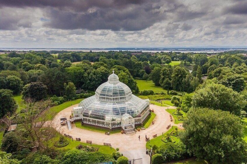 A large glass-domed conservatory surrounded by lush greenery and a park. 4