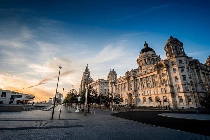 A historic building with domed architecture and a clock tower, surrounded by a paved plaza and street lamps. 3