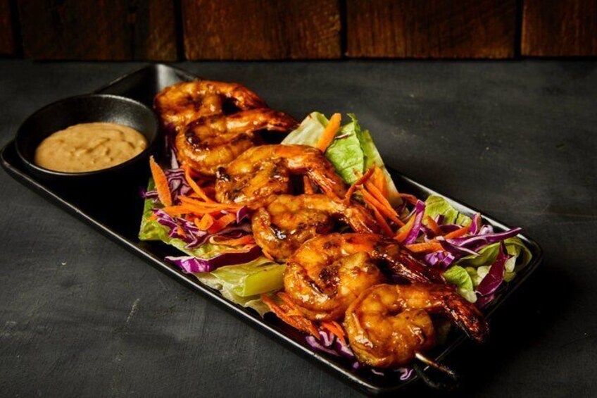 A dish of grilled shrimp with a side salad and dipping sauce. 4