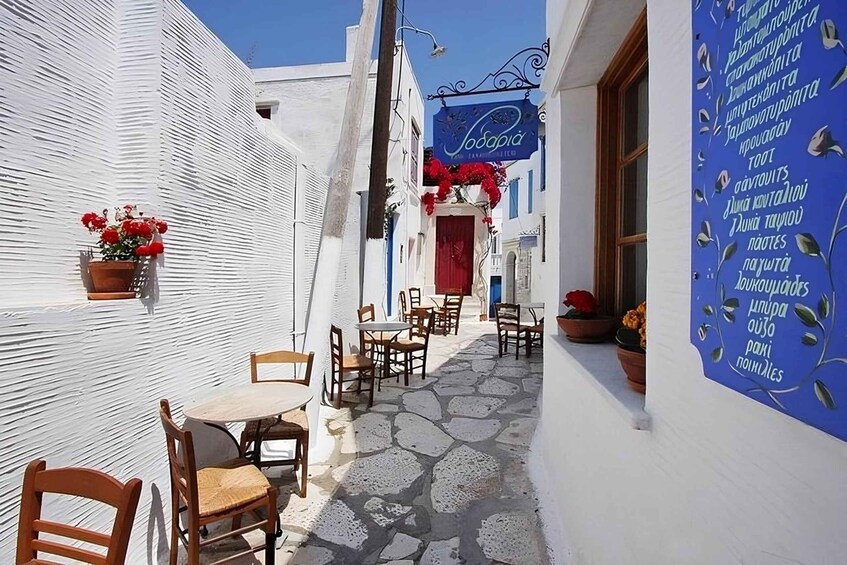 A narrow street with white buildings, a blue sign for 'Sofia,' and outdoor seating. 1