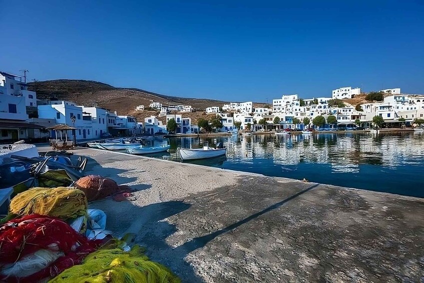 A coastal village with white buildings, boats docked at the pier, and a clear blue sky. 2