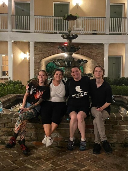 A group of people sitting on a stone bench in front of a decorative fountain. 2