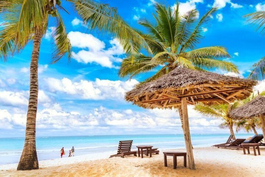 A beach with palm trees, thatched umbrellas, and lounge chairs. 3