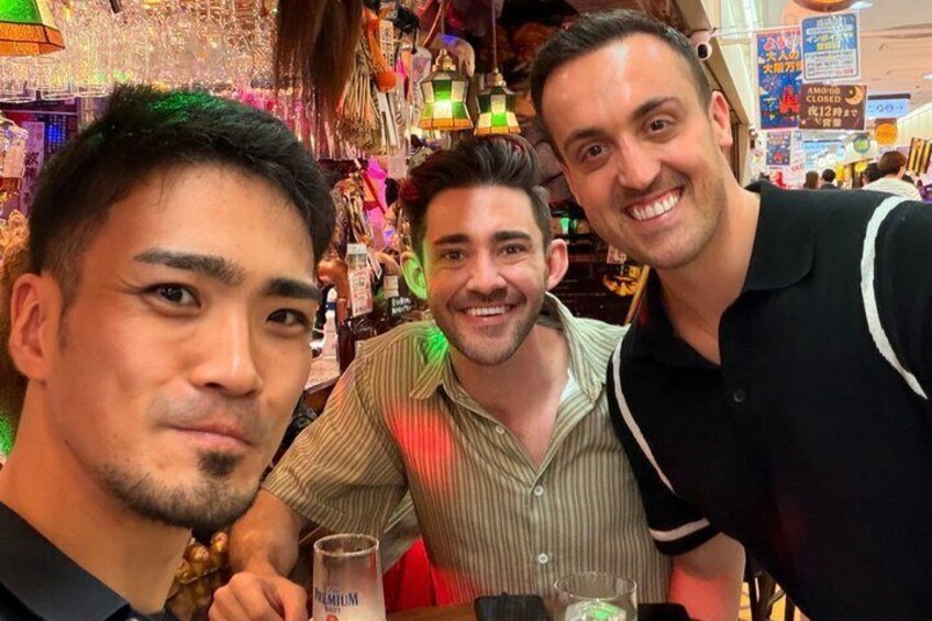 Three people in a bar with bottles and glasses. 3
