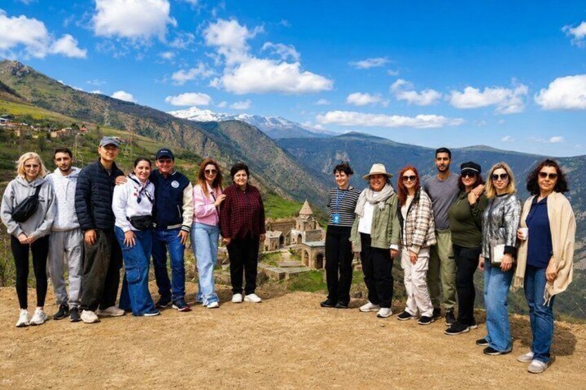 A group of people standing on a hill with a mountainous landscape and a castle in the background. 2