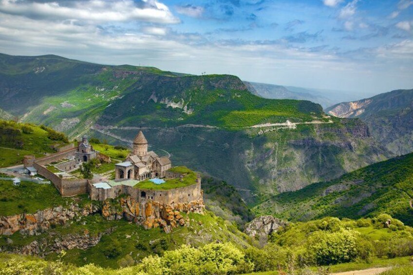A historic church on a hillside with a valley in the background. 1