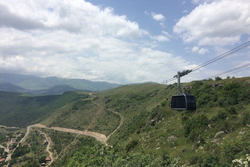 A cable car on a mountain, a winding road, and a valley below. 3