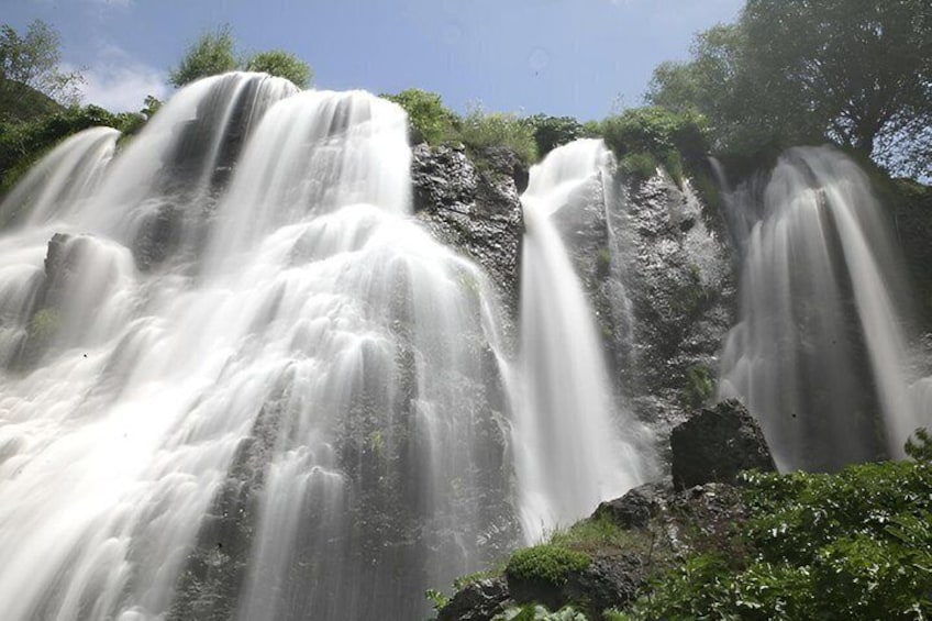 A multi-tiered waterfall surrounded by lush greenery. 4