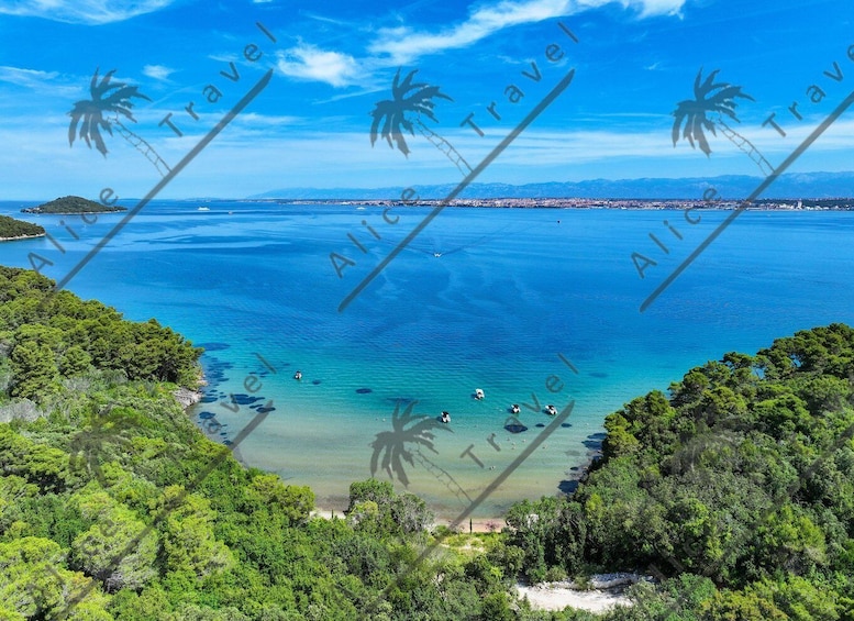 A coastal landscape with clear turquoise waters, dense green foliage, and a distant shoreline. 5