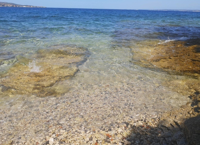 A rocky shoreline with clear water and distant land. 2
