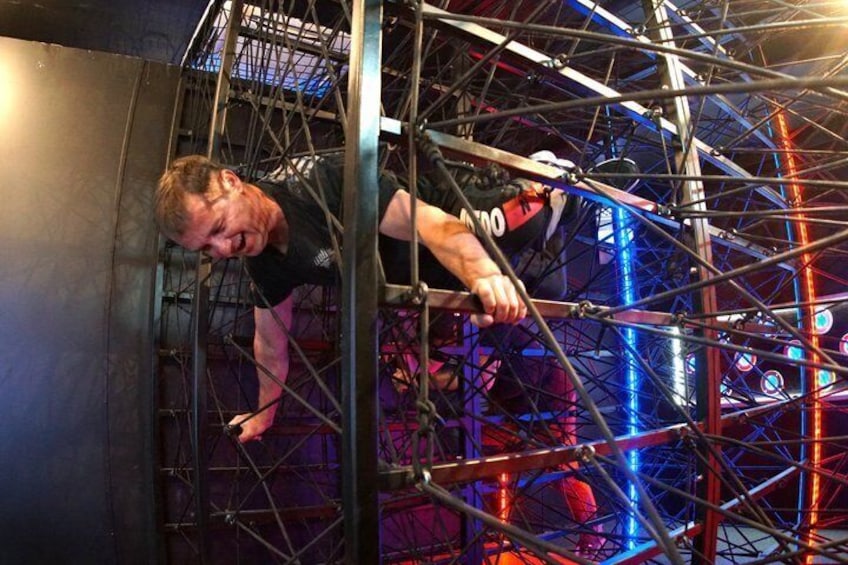 A person climbing a metal structure with a complex network of beams and cables. 5