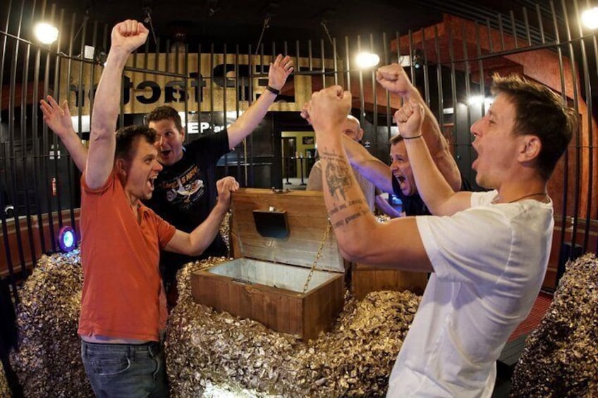 A group of people in a room with a wooden chest and a chain. 1