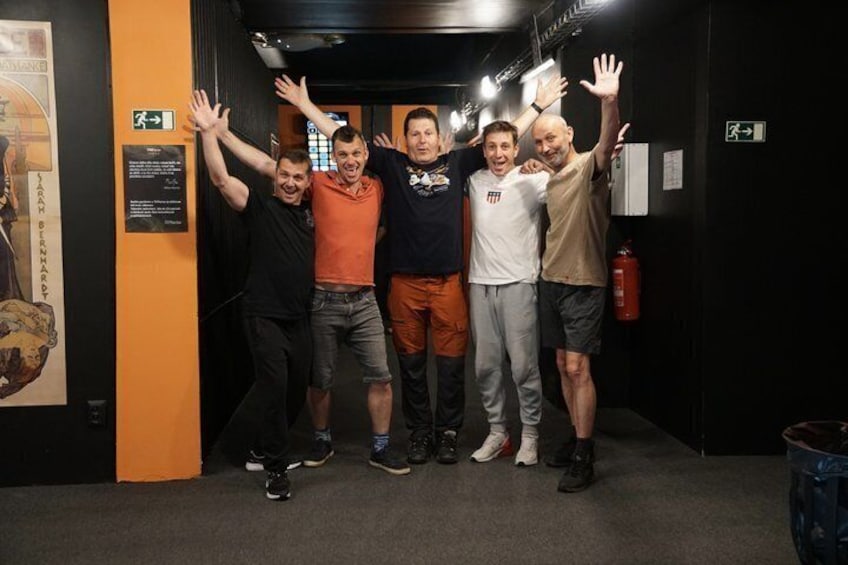 A group of people in a hallway with orange walls, a fire extinguisher, and emergency exit signs. 2