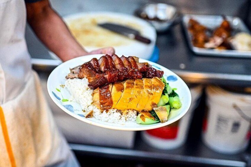 A person holding a plate with rice, a roasted meat dish, and vegetables. 2
