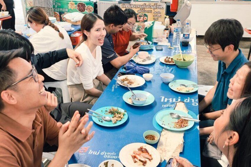 A group of people sitting around a table with food, engaged in conversation. 1