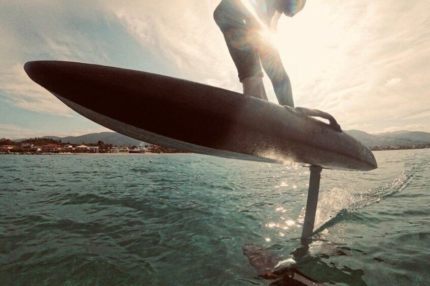 A person standing on a surfboard in the water with a sunset in the background. 1