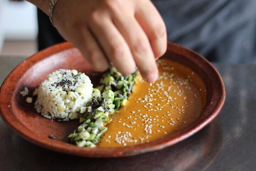 A person seasoning a dish with sesame seeds. 3