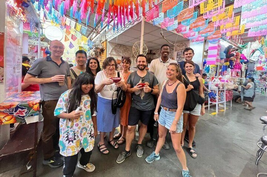 A group of people in a market with colorful decorations and various items for sale. 1