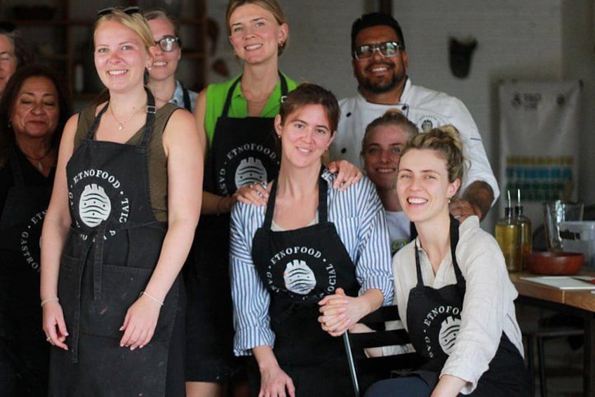 A group of people wearing aprons with a logo, standing in a kitchen setting. 3
