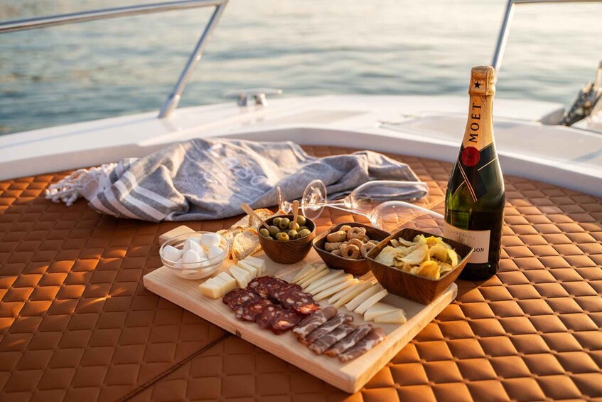 A boat with a table set for a meal, including cheese, olives, nuts, and a bottle of Moët champagne. 5