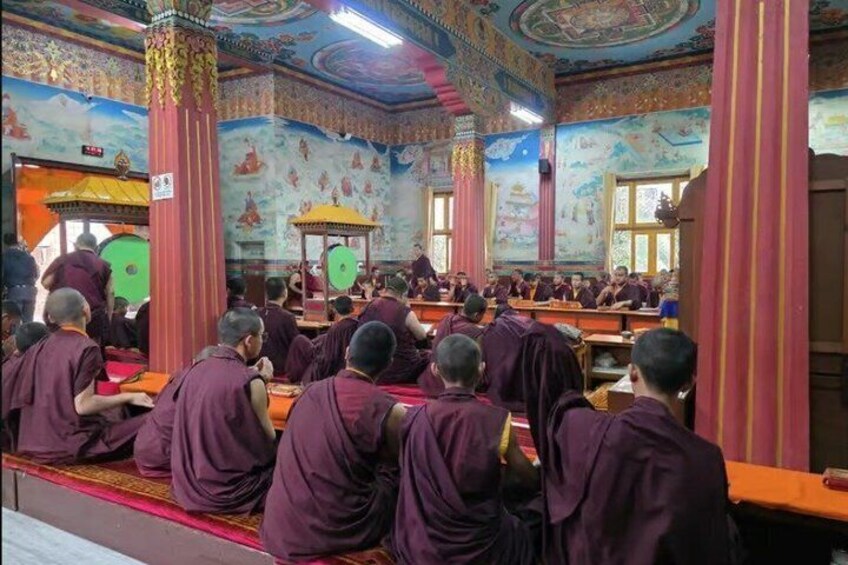 Monks in a colorful, ornately decorated hall. 3