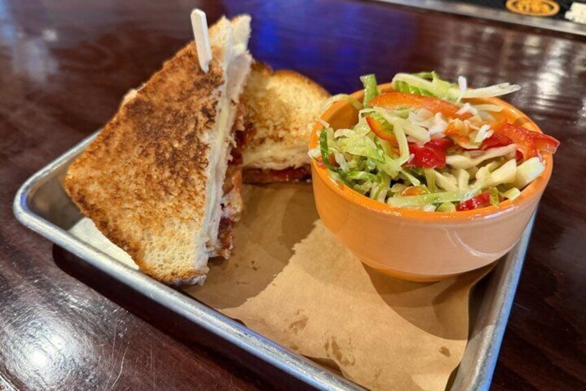 A grilled sandwich with toothpicks and a side salad in a bowl. 1