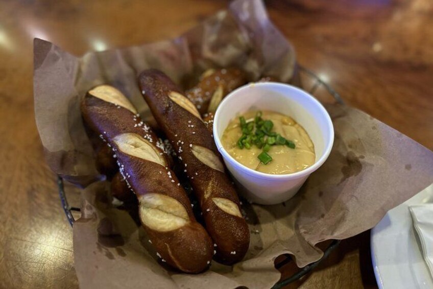 Two pretzel sticks with a dipping sauce in a small bowl. 3