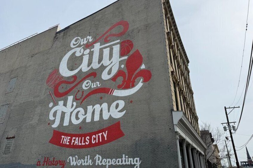 A building with a mural that says 'Our City, Our Home' and 'The Falls City.' 4