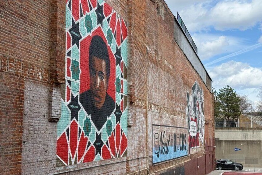 A brick building with a mural featuring a person and text. 2