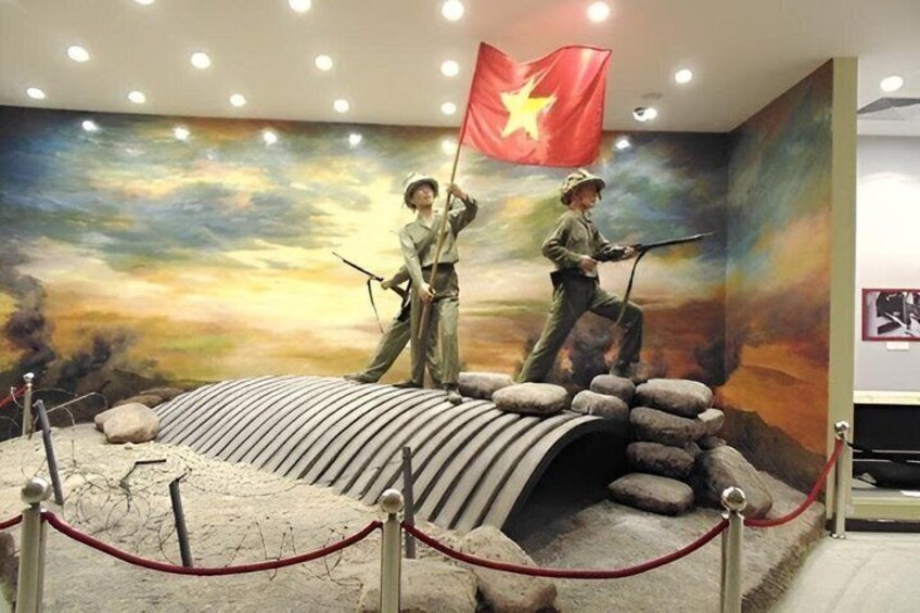 A museum exhibit with two soldiers, a flag, and a landscape mural. 5
