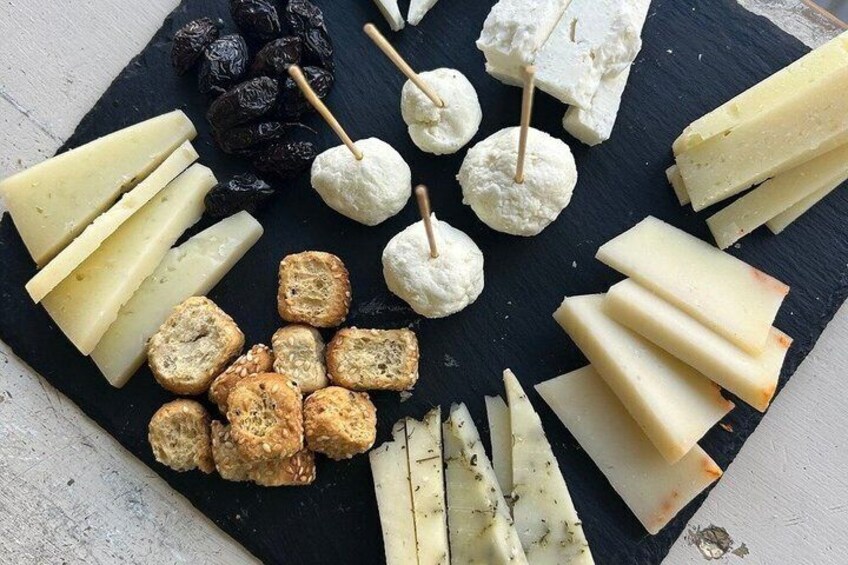 A cheese board with various cheeses, crackers, and grapes. 3