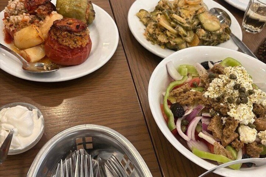 A table with various dishes including stuffed vegetables, a salad, and a bowl of olives. 1