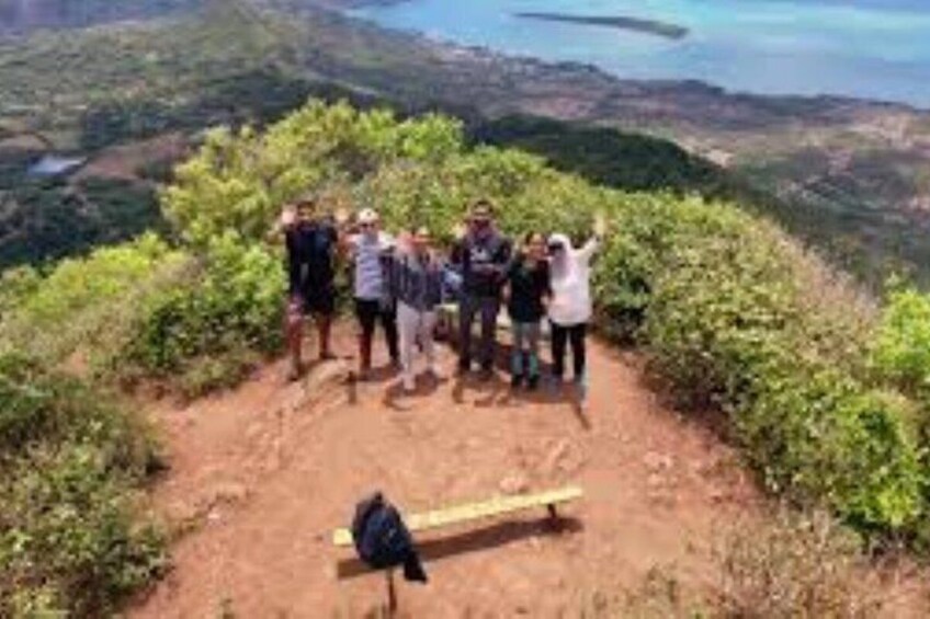 A group of people standing on a dirt path with a bench and greenery around. 4