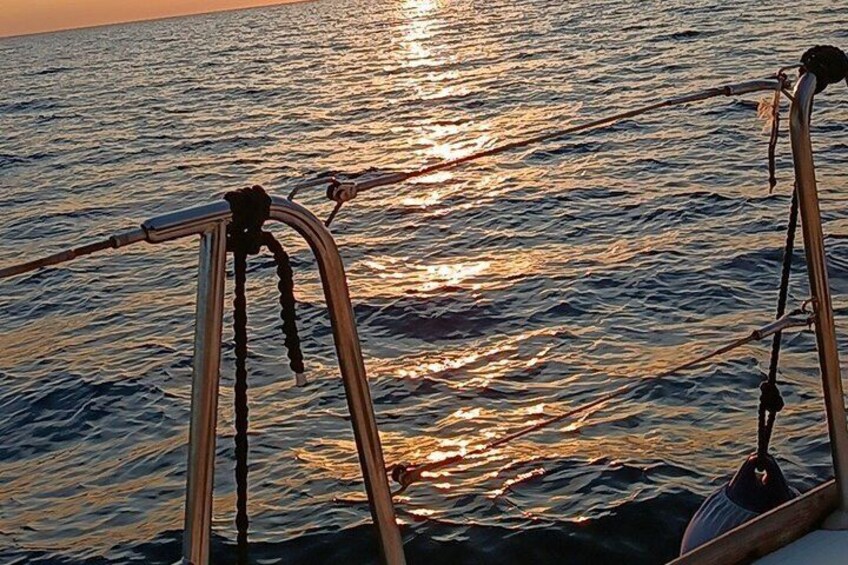 A boat's bow with metal railings and a wake in the water. 5