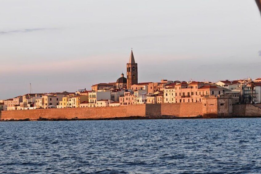 A coastal town with a prominent church tower, a fortified wall, and buildings along the waterfront. 4