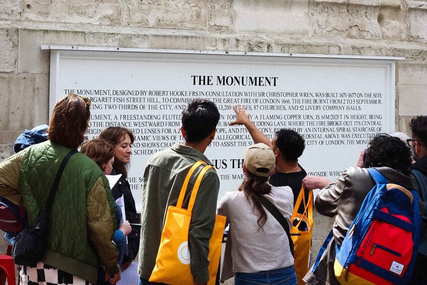 A group of people reading a sign about The Monument. 4