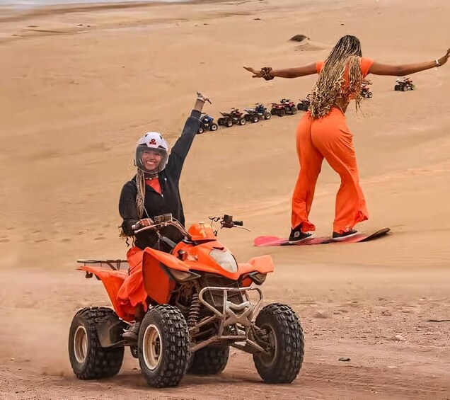 A person on an orange quad bike in a desert with sand dunes. 3