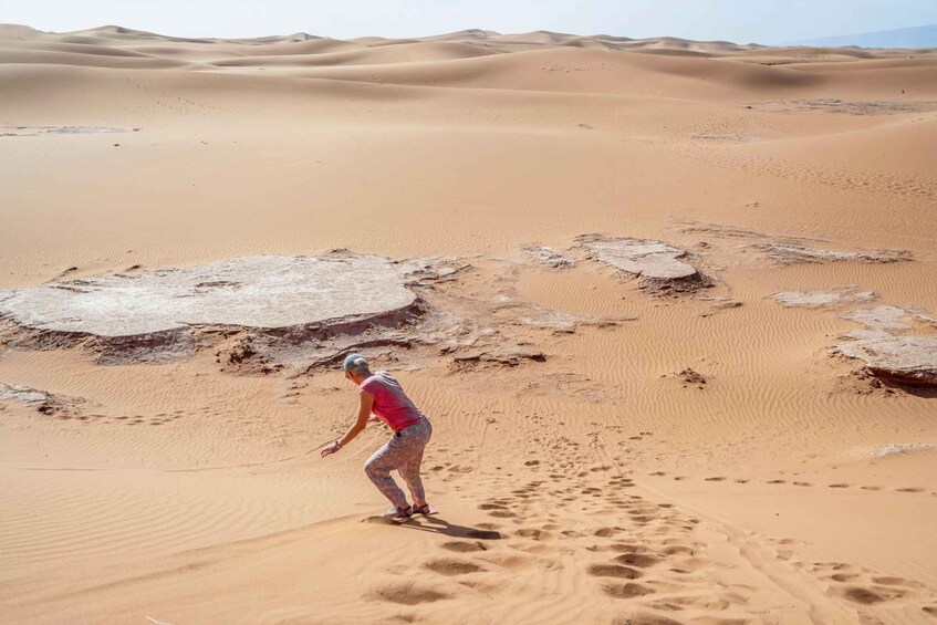 A person walking on sand dunes in a desert landscape. 5