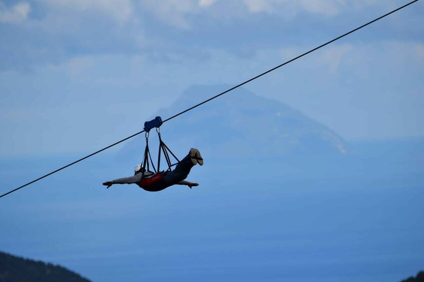A person suspended by a cable, with a mountainous landscape in the background. 2