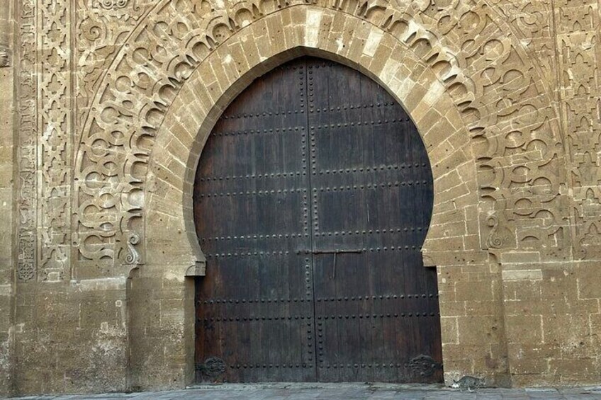 A large, ornate stone archway with a dark wooden door. 2