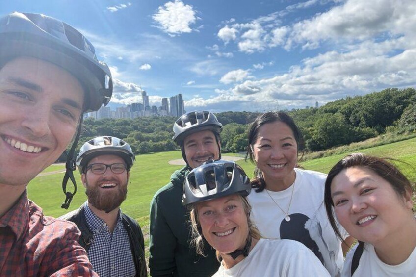A group of people wearing helmets, a grassy field, and a city skyline in the background. 2