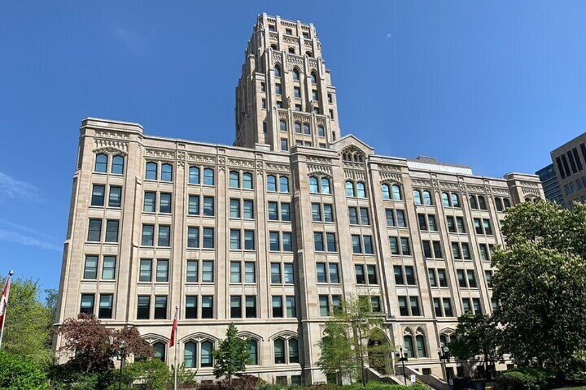 A large, historic building with a prominent tower, surrounded by trees and a clear blue sky. 3