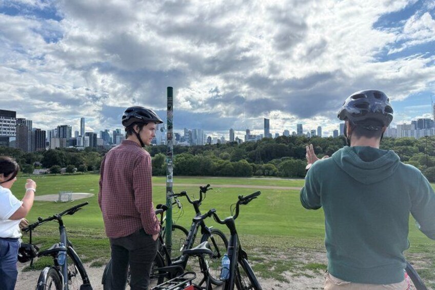 A park with bicycles, a city skyline in the background, and a cloudy sky. 1